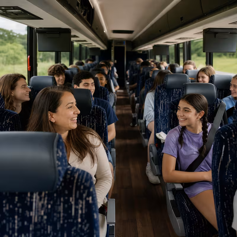 Group boarding a white charter bus for School Transportation transportation in Albuquerque