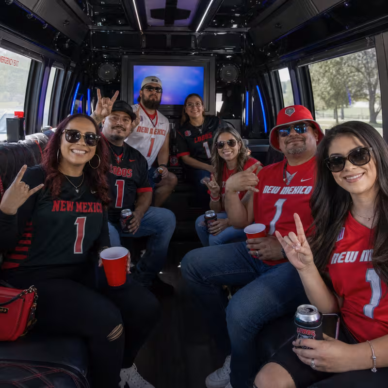 Group boarding a white charter bus for Sporting Event Transportation transportation in Albuquerque